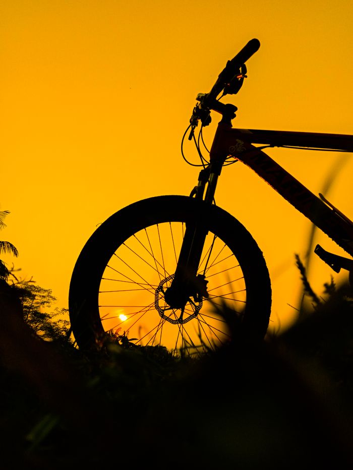 Dramatic bicycle silhouette against a vibrant sunset in Cumilla, Bangladesh.