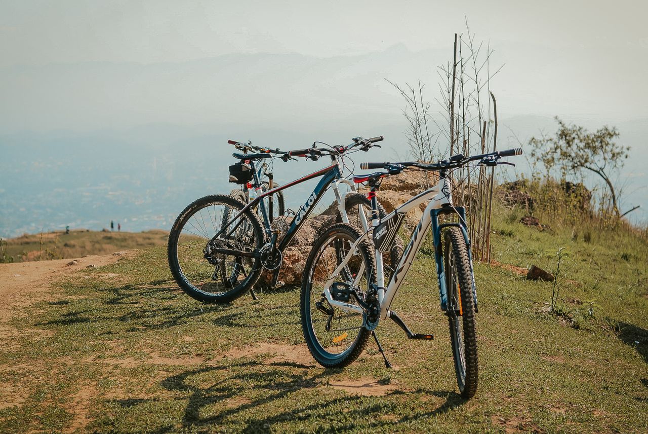 Two mountain bikes parked on a scenic hilltop path with a distant view of landscape.